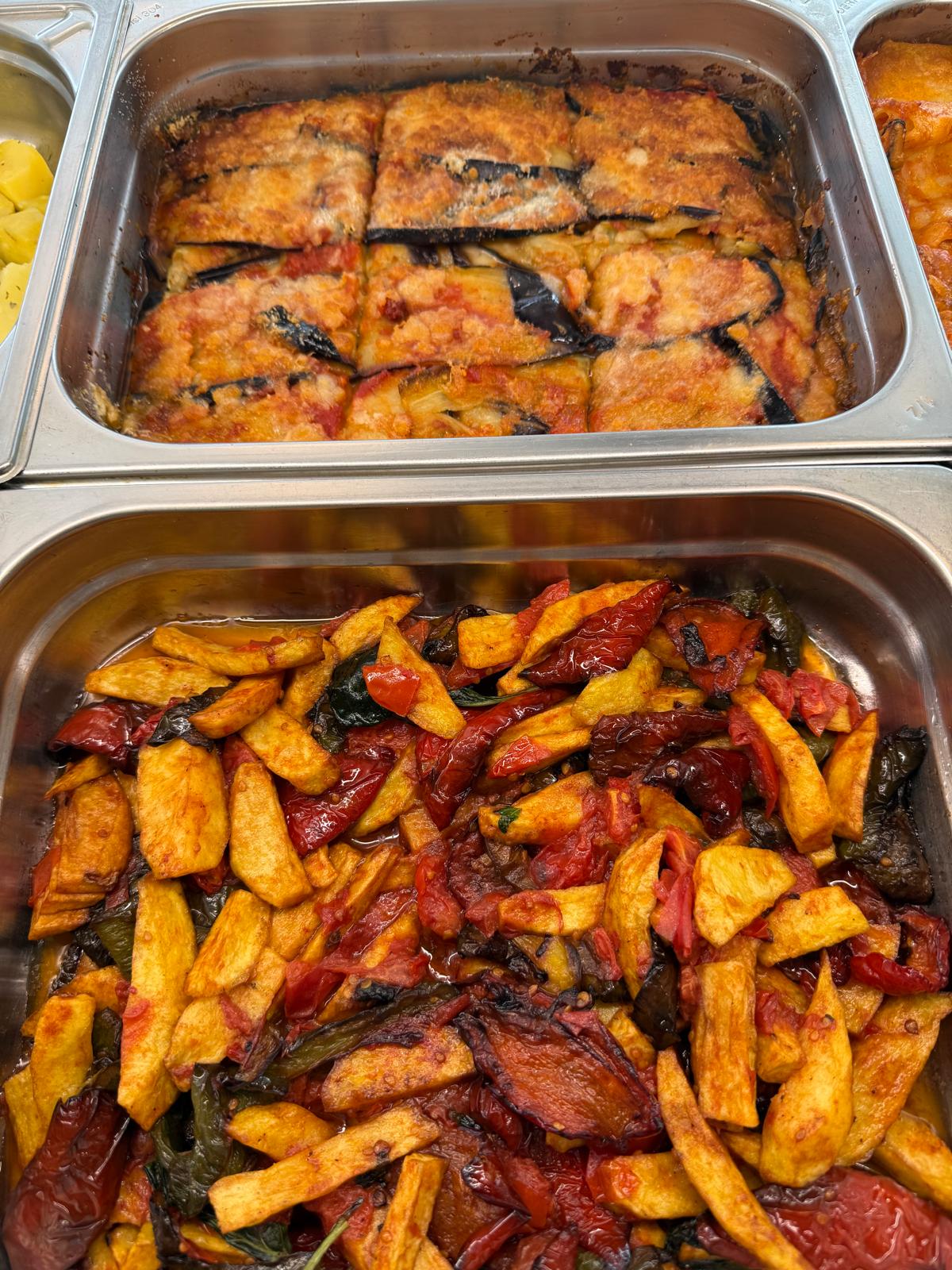 Parmigiana di melanzane e patate fritte con peperoni in vaschette d'acciaio al banco di Lo Spizzico